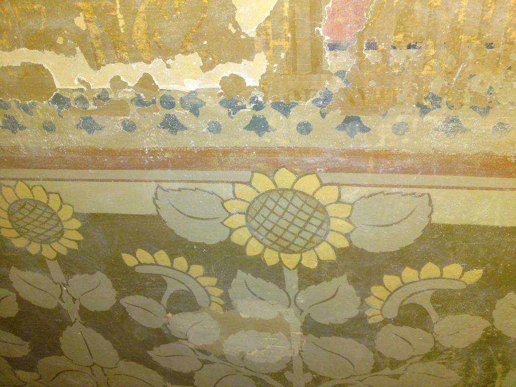 Restauratie van een geschilderde sjabloonrand met zonnebloemen op een oude wand