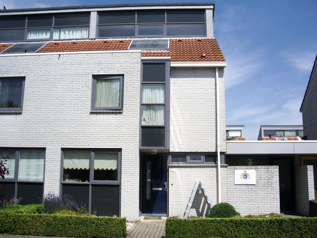Witte gevel met donkergrijze kozijnen en een donkerblauwe voordeur, de ladder nog bij de deur